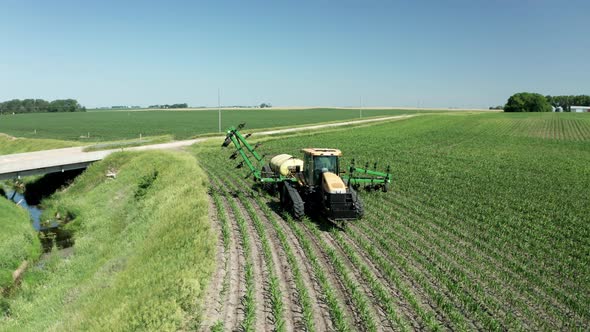 Pesticide sprayer attached to farm tractor opening arms, preparing to operate. Aerial. Series