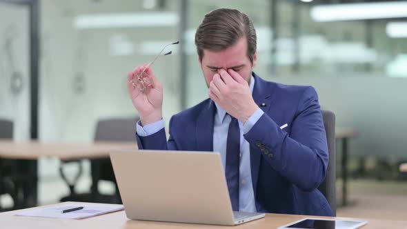 Stressed Young Businessman with Laptop Having Headache 