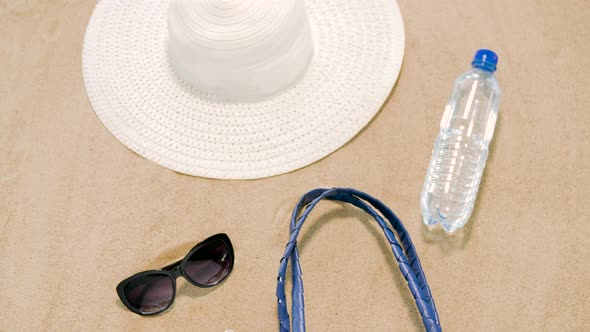 Beach Bag, Sunscreen, Sunglasses and Hat on Sand