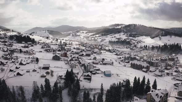 Aerial Footage of Small Mountain Village in Winter Time During Sunny Day with Epic Clouds