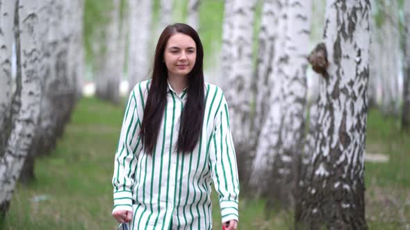 Girl Walks in a Birch Grove on a Spring Day