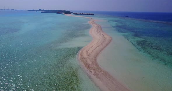 Natural fly over tourism shot of a sandy white paradise beach and aqua blue water background in best