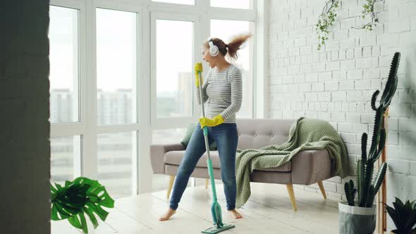 Happy Housewife Is Dancing and Singing During Housecleaning, She Is Listening To Music in Headphones