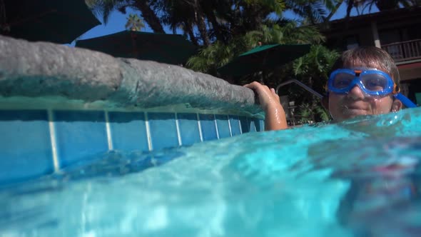 Underwater shot of a boy playing in a pool at a hotel resort.