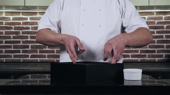 Chef is Demonstrating a Modern Pepper Mill in the Restaurant Kitchen