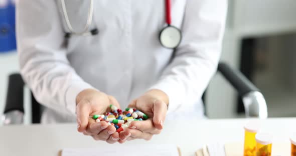 Doctor Holds Handful of Multicolored Medical Pills in Hands Closeup