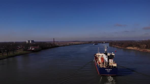 Freight Ship Cruising On Tranquil Dutch River Of Oude Maas In The Netherlands. - Aerial Wide Shot