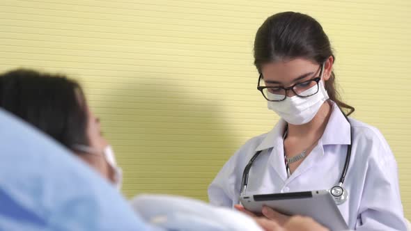 Doctor Wearing Face Mask Proficiently Talks with Patient at Hospital Ward