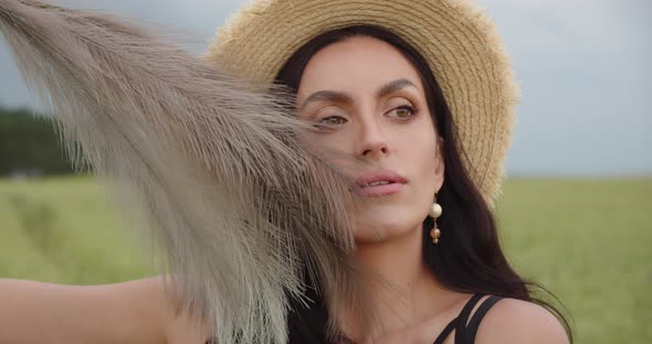 Girl In A Field In A Straw Hat Caresses Herself With A Featherbed