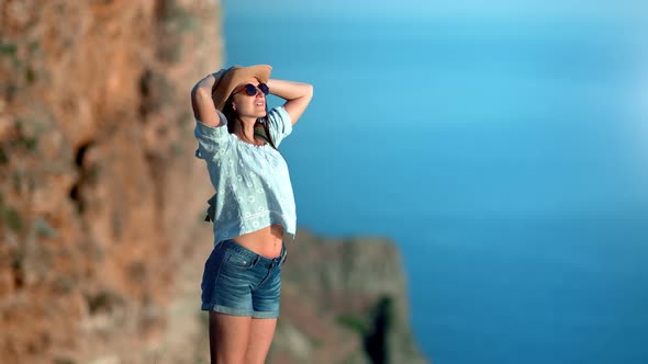 Relaxed Travel Hipster Female Enjoying Sunbathing Standing on Mountain Admiring Sea