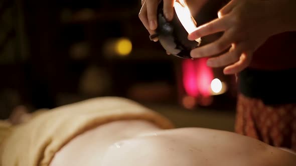 Massage therapist pouring warm oil on clients body making relaxing massage