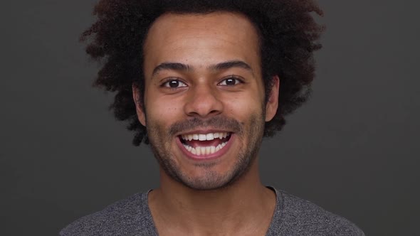 Dark Skinned Young Man with Afro Haircut Having Fun Showing His White Teeth Ang Tongue Over Charcoal