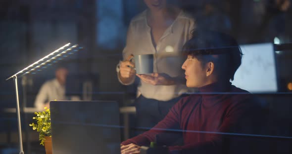 Businesswoman Bringing Coffee To Colleagues Working Together at Night in Office