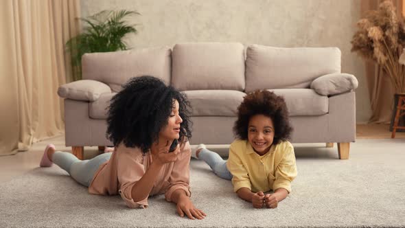 African American Woman and Litle Girl Watching TV Switching Channels with Remote Control