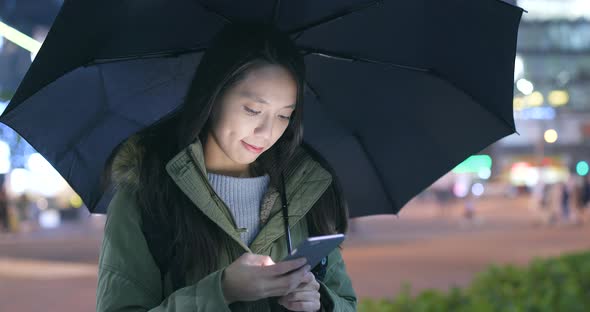 Woman using smart phone in the city at rainy day