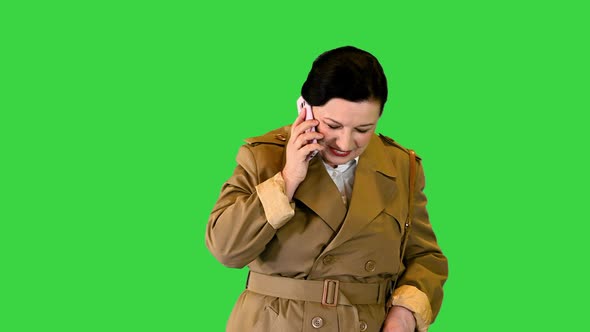 Mature Brunette Woman in Trendy Outfit Making a Call While Walking on a Green Screen Chroma Key