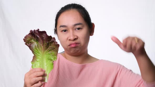 Asian woman hates fresh salad on white background in studio. Diet and Healthy food concept.