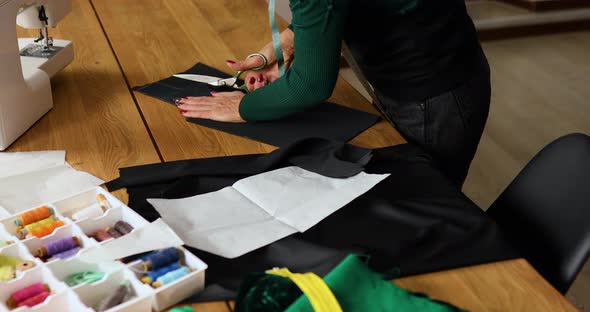 Step by step, Woman dressmaker hands cutting material with scissors on table