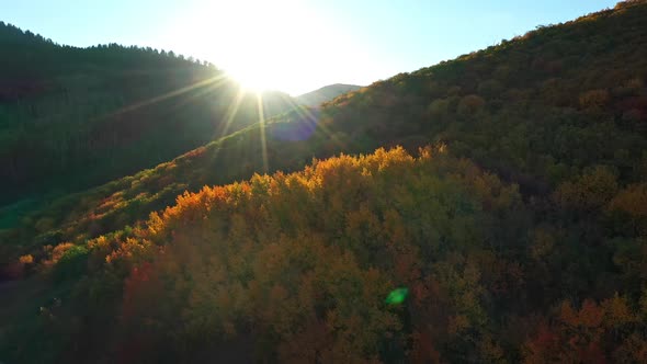 Flying over road looking towards the sun peaking over mountains