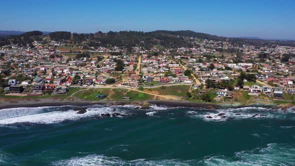 aerial: view of infiernillo beach in the city of pichilemu also overlooking the town with black sand