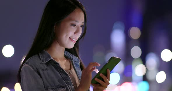 Woman using cellphone in city of Taipei at night