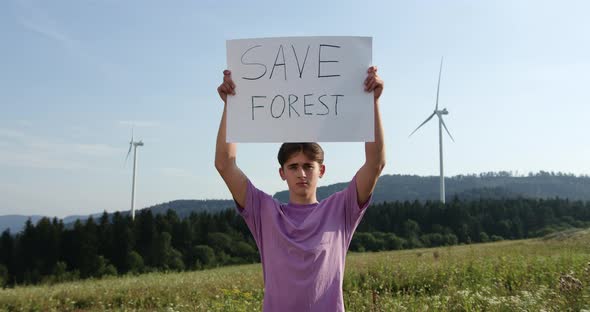 Outdoor of Men Activist with Save Forest Ecology Poster. In Background Forest and Wind Turbine