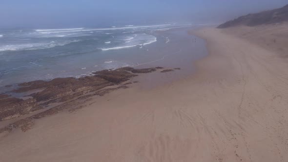 Drone Flying Over Pristine Coastline with People Seen Walking