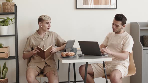 Two Men Sitting at Desktop and Chatting