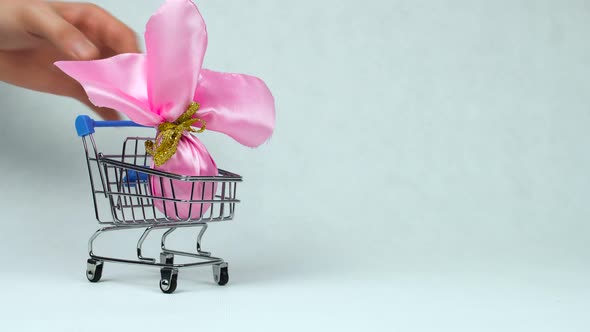 Wrapped Easter Egg As a Gift Is Put Into the Toy Shopping Cart During Pascha or Christian Feast