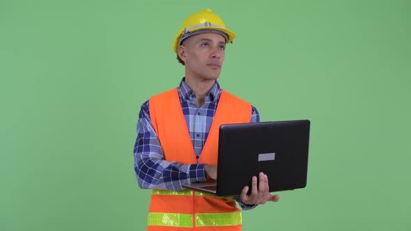 Happy Multi Ethnic Man Construction Worker Thinking While Using Laptop