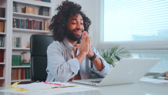 Cheerful Young Middle Eastern Man Prays Emotionally Sits in Office