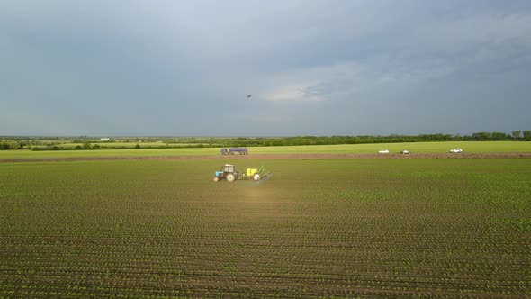 Tractor with Movable Sprinkler System and Irrigation Machine is Watering the Growing Wheat on Field