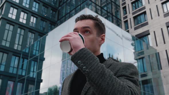 Portrait of Ambitious Businessman Stand in the City Center Street and Drinking Coffee. Motivated