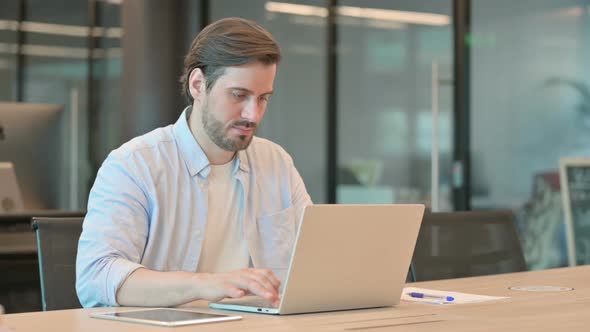 Mature Adult Man with Laptop Thinking in Office