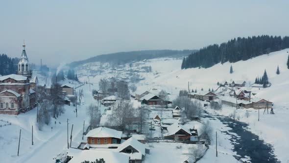 Aerial View of a Village in the Snow on the Bank of a Frozen River