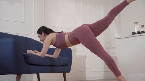 Woman using couch for leg and planking exercise at home