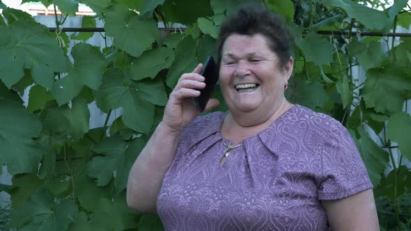 Mature old woman talking by smartphone and laughing. Modern technology.