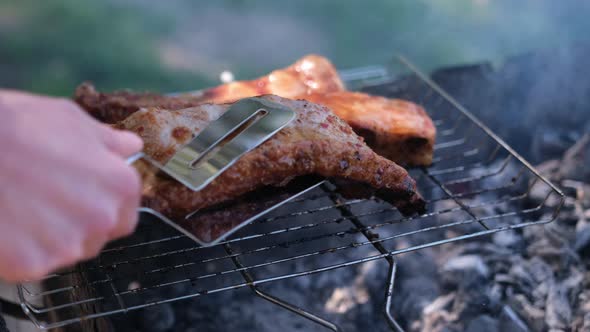 Flipping Delicious Beef or Pork Ribs Frying on a Charcoal Grill with Tongs