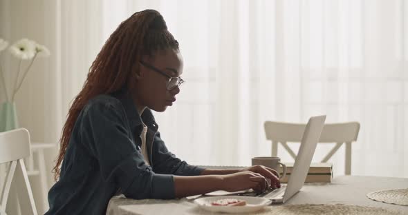 African American Student Writing Article on Laptop