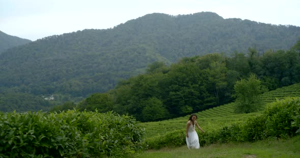 Laughing Woman Is Running in Countryside Between Tea Plantations in Summer Day