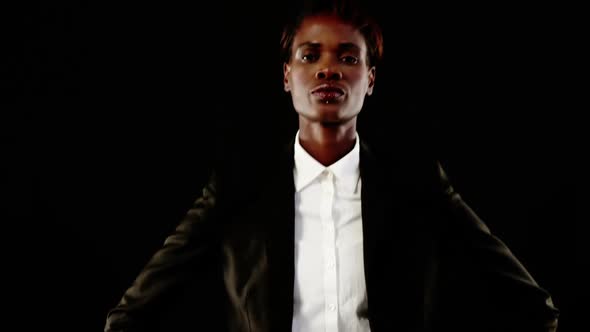 Androgynous man posing in blazer against black background