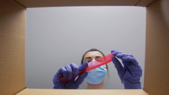 Woman in Mask Unpacking Parcel Box with Cosmetics