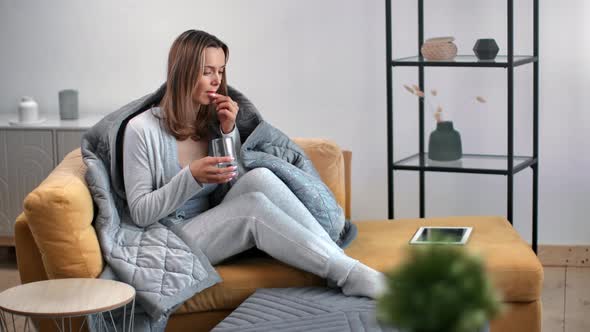 Unwell Female Drinking Pill Water Glass Influenza Flu Wrapped in Blanket