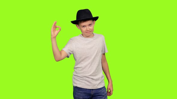 Teenage Boy in White T-shirt and Black Hat Showing OK Sign alt