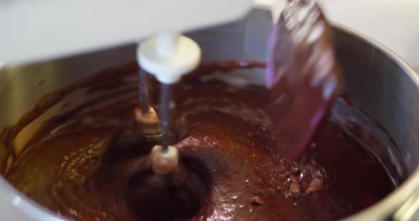 A chef using an electric mixer and a spatula to make delicious vegan chocolate cake batter while bak