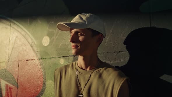 Stylish Man Turning Head to Camera in Sunbeams at Skatepark