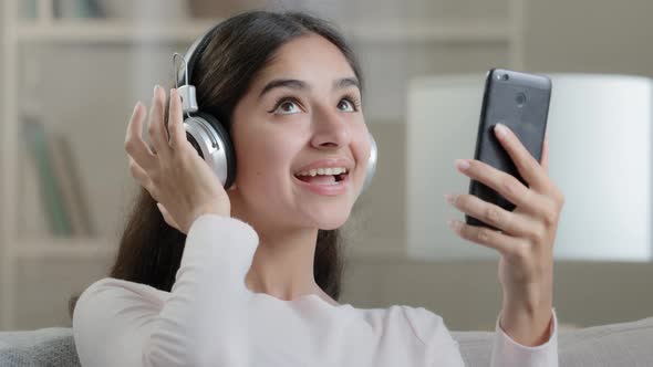 Joyful Artistic Arabic Woman Teenager Wears Headphones Earphones Listen Music Melodies Choose Audio