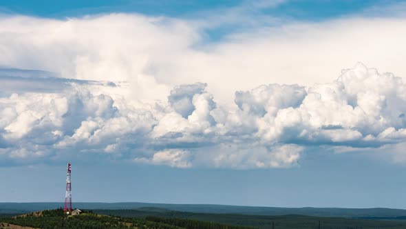 Movement of Cumulus Clouds Behind a Hill with a TV Tower on Top