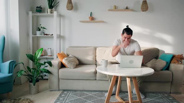 Young Man with Laptop Wins Joy and Happy with His Success Sitting on Couch at Home