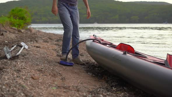 Young Man Inflates His Kayak and Prepares It for Paddling in a Lake or Sea. Slowmotion Shot